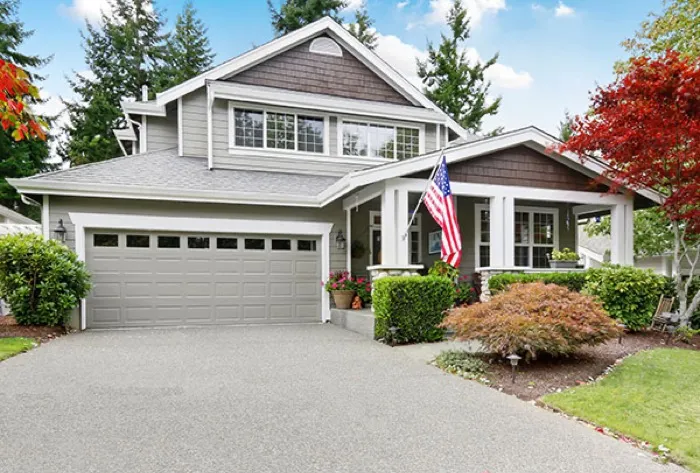 A suburban home with an American flag and a landscaped driveway