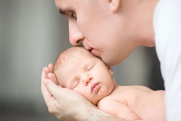 A father kissing his newborn baby