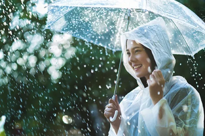 A woman smiling under a clear umbrella in the rain